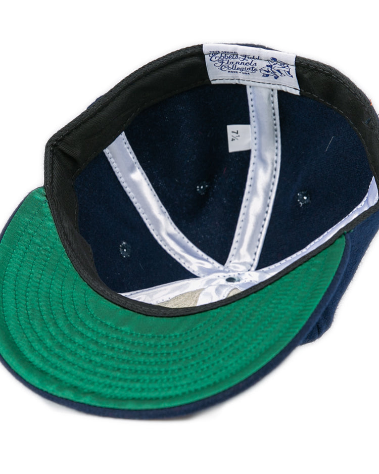 A Bucknell University 1965 Vintage Ballcap by EFF, navy wool and made in the USA, turned inside out to show its green brim underside, white satin lining, and a size 7 1/4 tag.