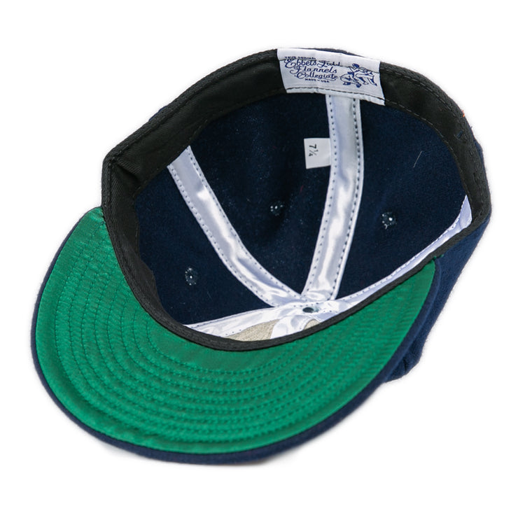 The Ebbets Field Flannels University of Mississippi 1969 Vintage Ballcap in navy features a green underbrim, white satin lining, size tag 7 1/4, and manufacturer label—classic details visible from underneath.
