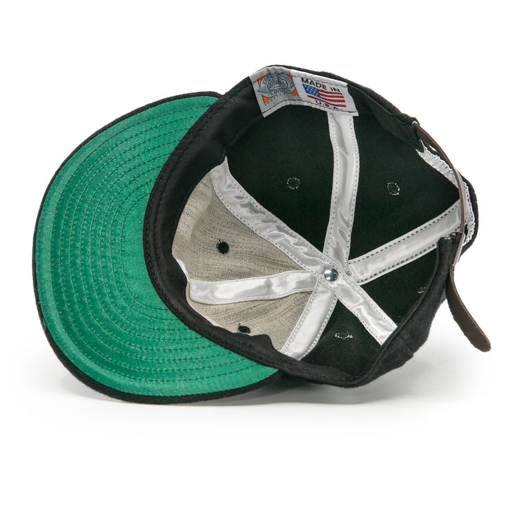 The image shows the inside of an EFF Bisbee-Douglas Copper Kings 1951 Vintage Ballcap, featuring a green undervisor, white fabric strips, and a Made in USA tag sewn into the inner band.