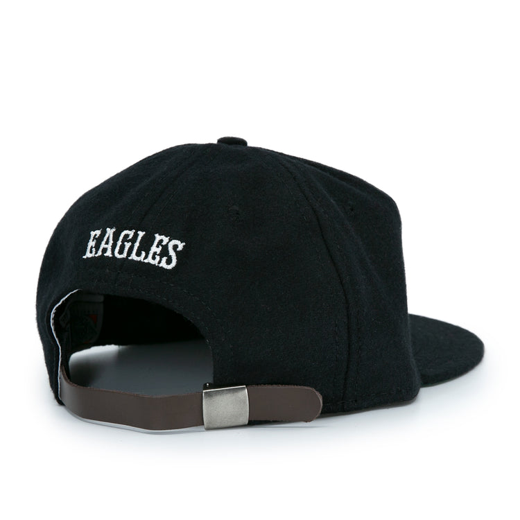 The EFF Brooklyn Eagles Vintage Inspired Ballcap is a black baseball hat with EAGLES embroidered in white above an adjustable brown strap and metal clasp, shown from the back.