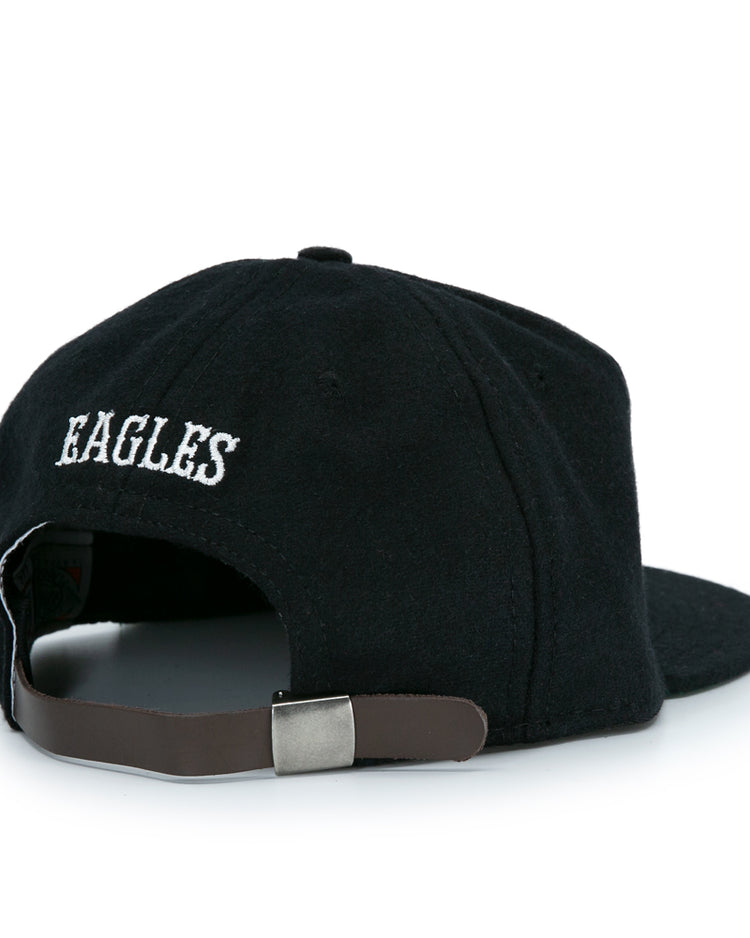 The EFF Brooklyn Eagles Vintage Inspired Ballcap is a black baseball hat with EAGLES embroidered in white above an adjustable brown strap and metal clasp, shown from the back.