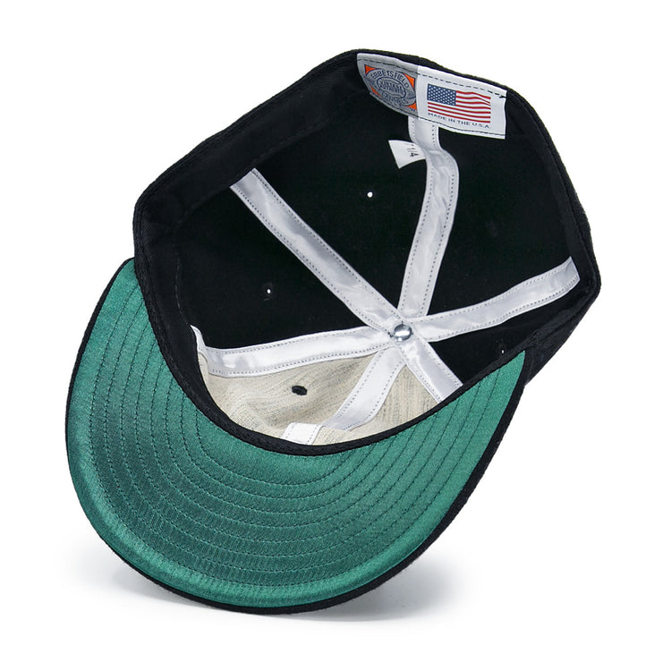 A close-up of the Brooklyn Eagles Vintage Inspired Ballcap by EFF shows its green brim, white lining, and an American flag tag sewn inside the crown.