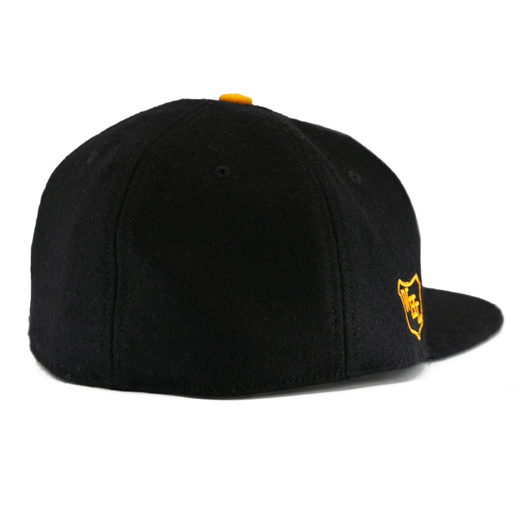 The EFF Brandon Wheat Kings 1955 Vintage Ballcap is a black wool cap with a flat brim, a small yellow top button, and a yellow shield logo on the front for classic hockey style.