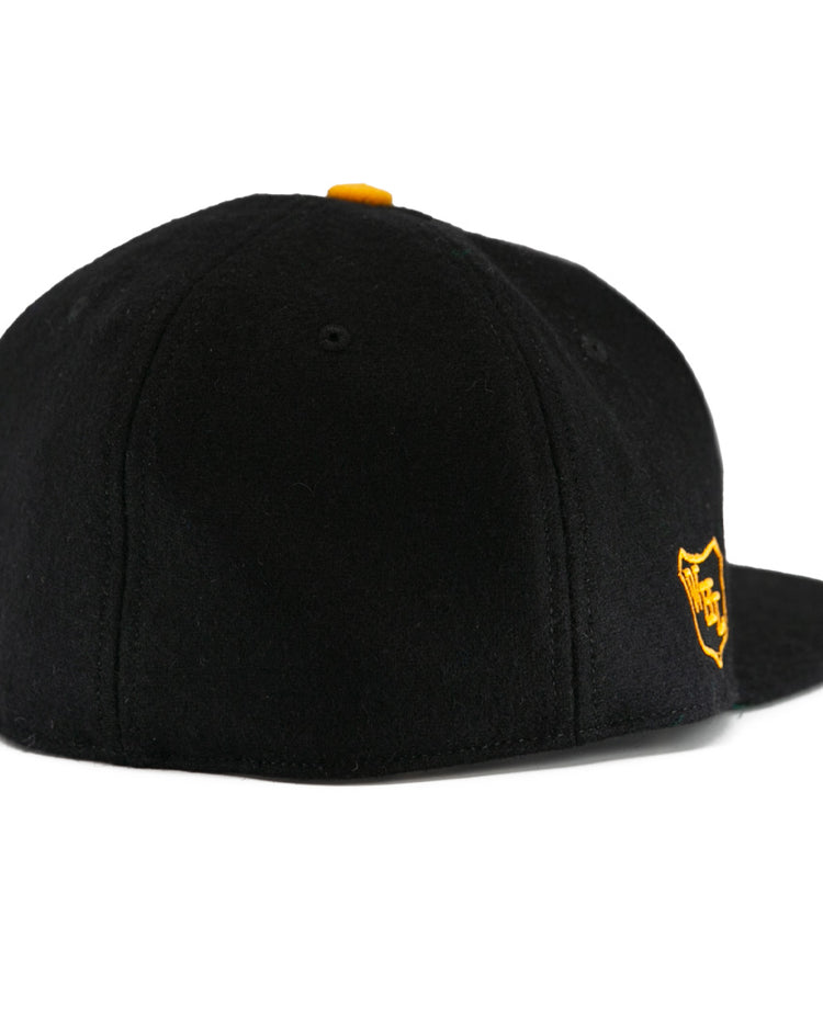 The EFF Brandon Wheat Kings 1955 Vintage Ballcap is a black wool cap with a flat brim, a small yellow top button, and a yellow shield logo on the front for classic hockey style.