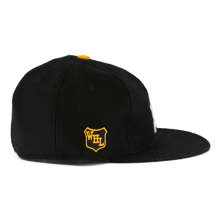 The EFF Brandon Wheat Kings 1955 Vintage Ballcap is a black wool flat-brim hat with a yellow top button and a side patch featuring a yellow and white shield with WFL, inspired by classic hockey styles.