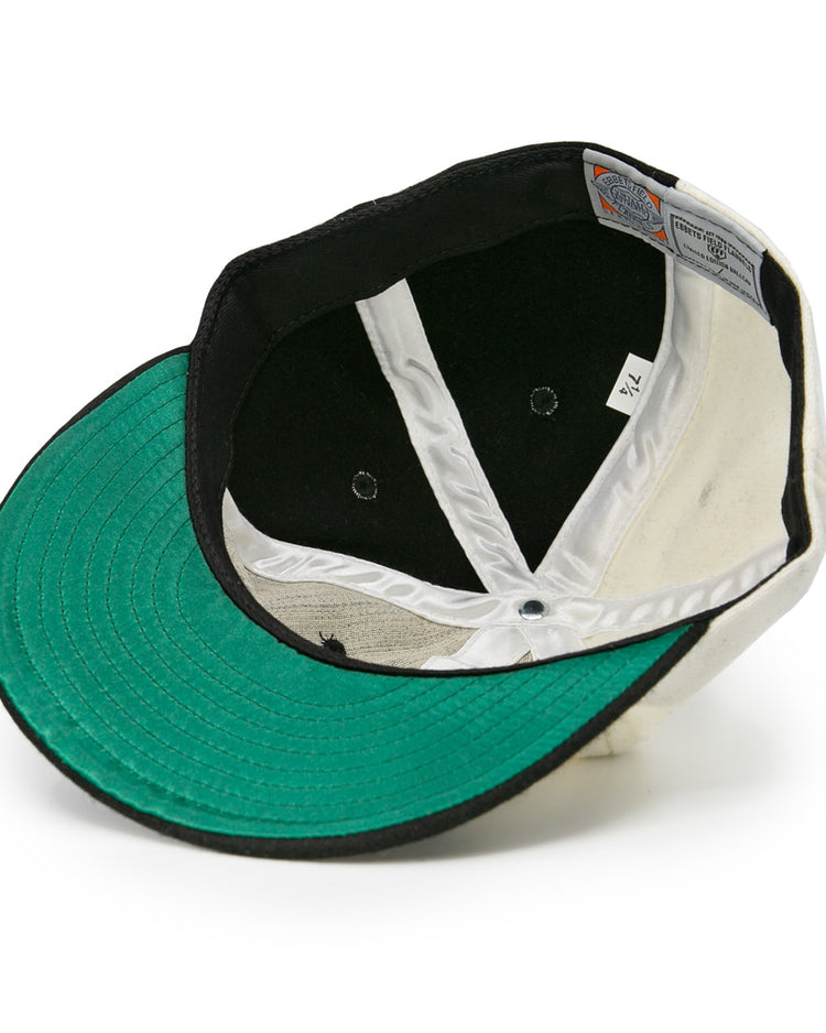 The image shows the inside of an EFF Bacharach Giants 1924 Vintage Ballcap, featuring a green brim, white interior panels, black lining, visible stitching, and a size tag.