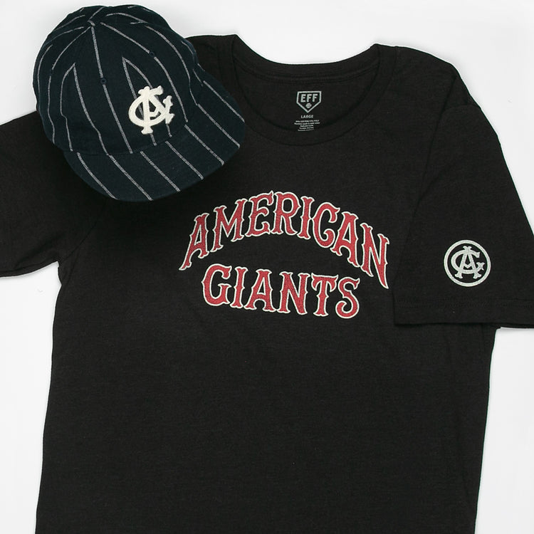 A black Chicago American Giants T-Shirt by EFF with red and white lettering and a sleeve logo patch sits beside a navy pinstriped cap with a white overlapping logo, celebrating the legacy of Black baseball.