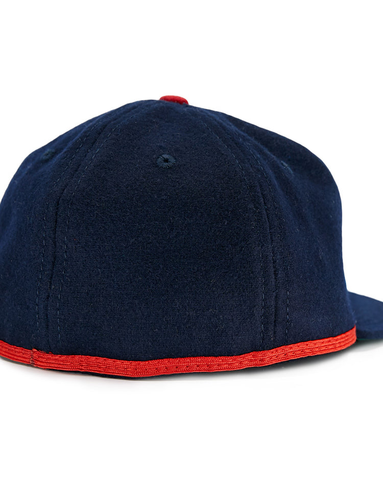 The EFF Cleveland Buckeyes 1947 Vintage Ballcap is a dark blue wool cap with visible stitching, flat brim, red trim along the edge, and a small red top button—shown from the back.