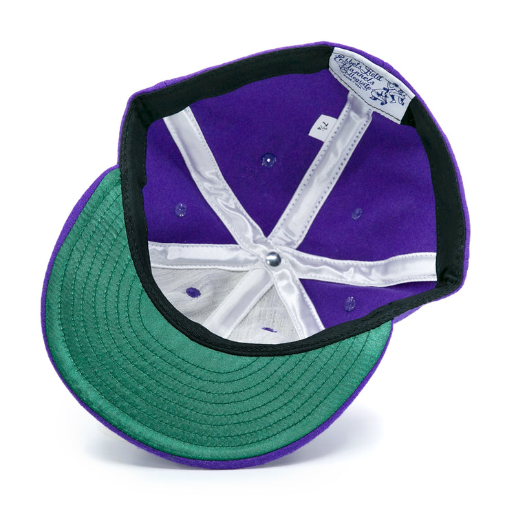 The EFF Cleveland Falcons 1936 Vintage Ballcap is a purple wool cap shown upside down, displaying its green underbrim, white inner lining, sewn crown labels, and an adjustable leather strap.