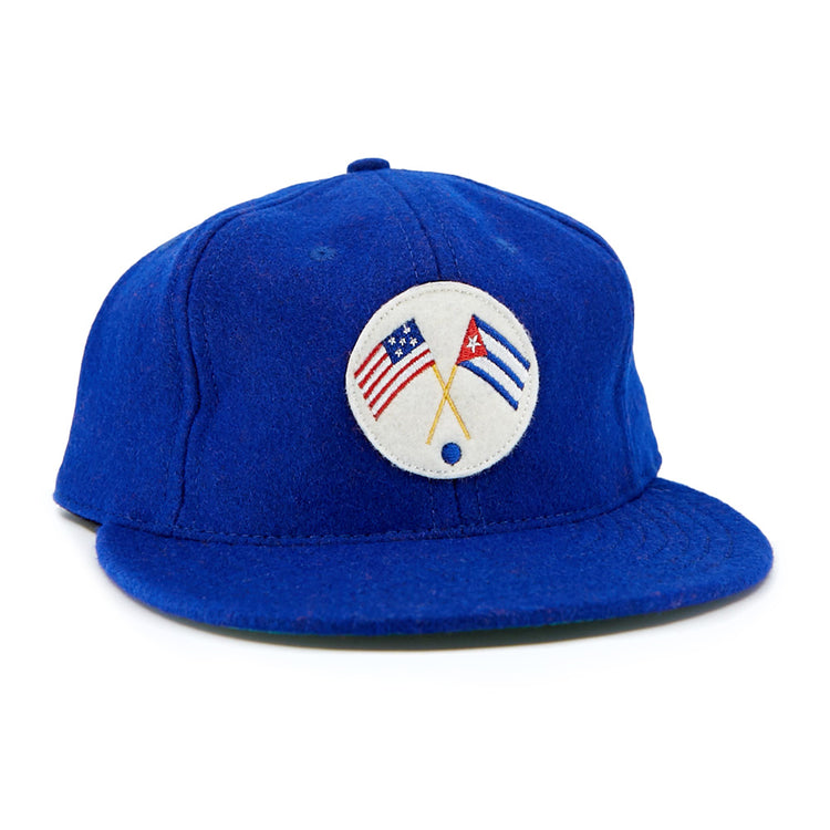 The EFF Cuban Stars 1932 Vintage Ballcap is a royal blue cap with a round white front patch featuring crossed American and Cuban flags, inspired by the East-West League’s classic design.