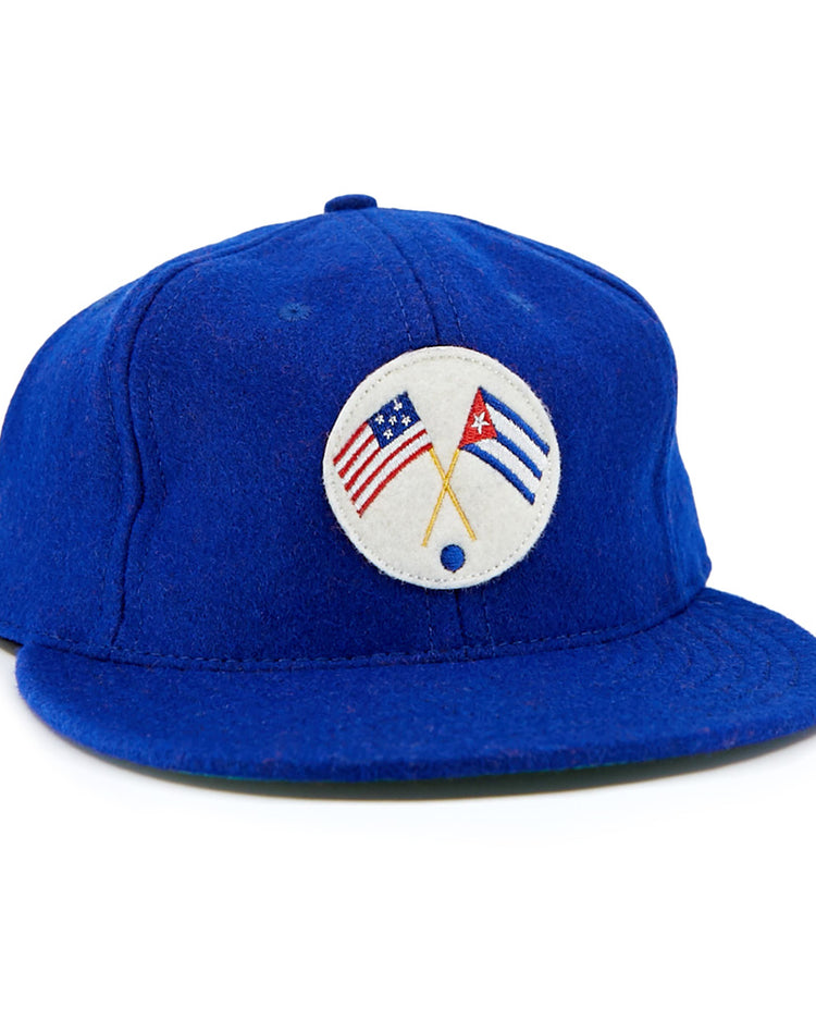 The EFF Cuban Stars 1932 Vintage Ballcap is a royal blue cap with a round white front patch featuring crossed American and Cuban flags, inspired by the East-West League’s classic design.