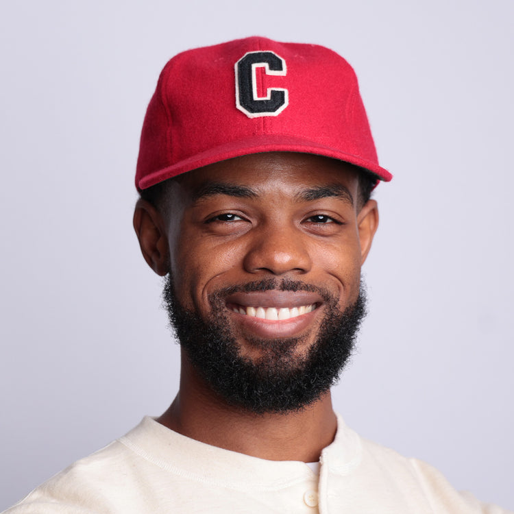 A bearded man smiles in a light shirt and the EFF Coastal Carolina University 1968 Vintage Ballcap—a red hat with a bold black and white C—against a plain light background.