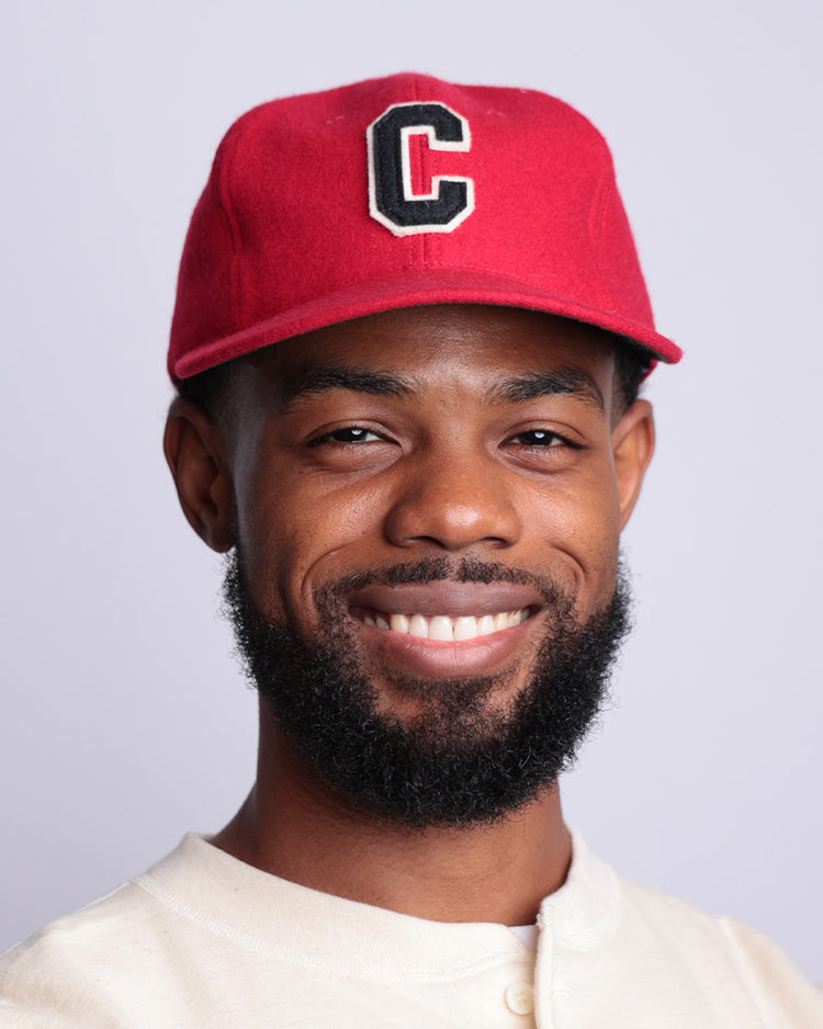 A bearded man smiles in a light shirt and the EFF Coastal Carolina University 1968 Vintage Ballcap—a red hat with a bold black and white C—against a plain light background.