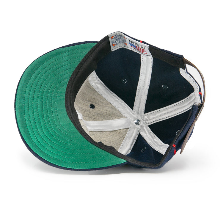 An overhead view of the EFF Danville Veterans 1932 Vintage Ballcap shows a green underbill, black and white panels, a leather strap with metal buckle, and a visible Made in USA tag near the rim.