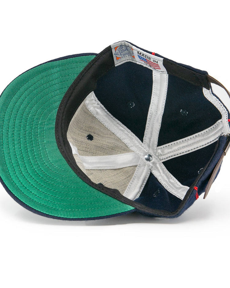 An overhead view of the EFF Danville Veterans 1932 Vintage Ballcap shows a green underbill, black and white panels, a leather strap with metal buckle, and a visible Made in USA tag near the rim.