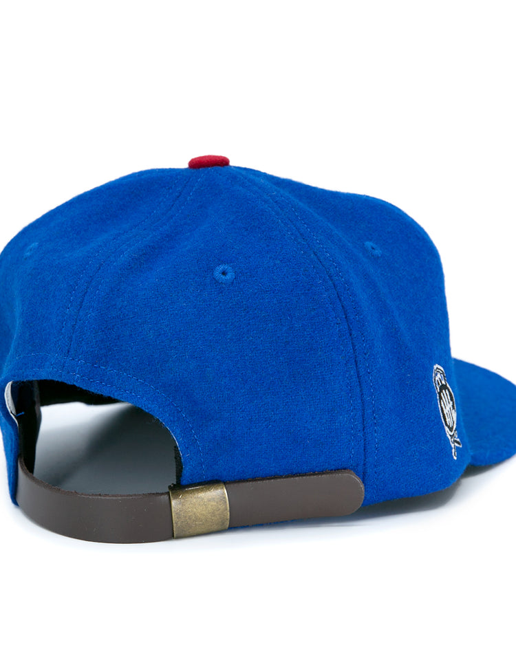 The EFF Detroit Olympics Vintage Ballcap is blue wool, shown from the back with a brown leather strap, brass clasp, a side embroidered logo, and a red top button inspired by classic International Hockey League style.