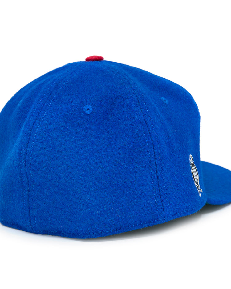 The EFF Detroit Olympics Vintage Ballcap, shown in royal blue wool with a red top button, has an embroidered International Hockey League logo on the right and a visible adjustable leather strap, displayed on a white surface.
