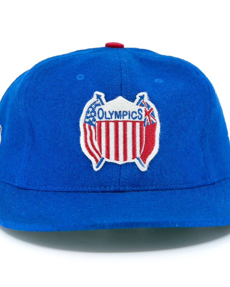 The EFF Detroit Olympics Vintage Ballcap is a royal blue wool cap with a classic Olympics logo—crossed bats and a red, white, and blue shield—plus an adjustable leather strap and an embroidered side patch.