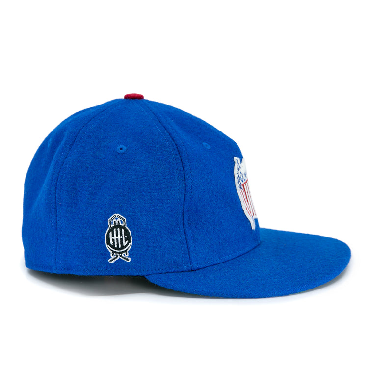 The Detroit Olympics Vintage Ballcap by EFF is a royal blue wool cap with a slightly curved brim, white and black side logo, red top button, and an adjustable leather strap for the perfect fit.