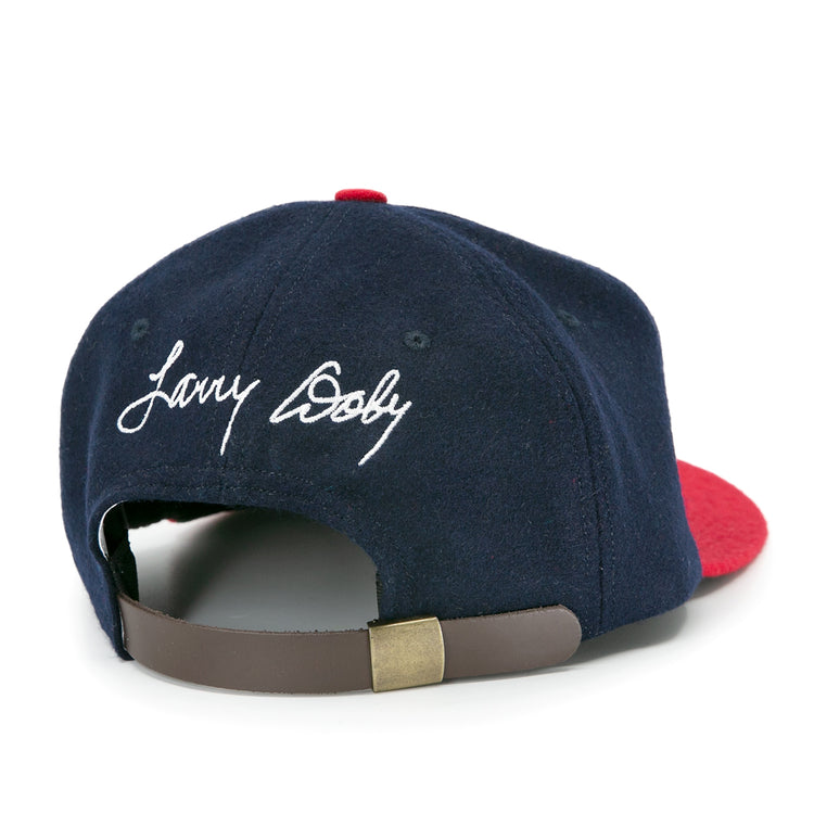 The Ebbets Field Flannels Larry Doby Signature Series Ballcap, in navy blue and red, features his name in white script above an adjustable brown leather strap with a brass clasp—a timeless limited edition cap.