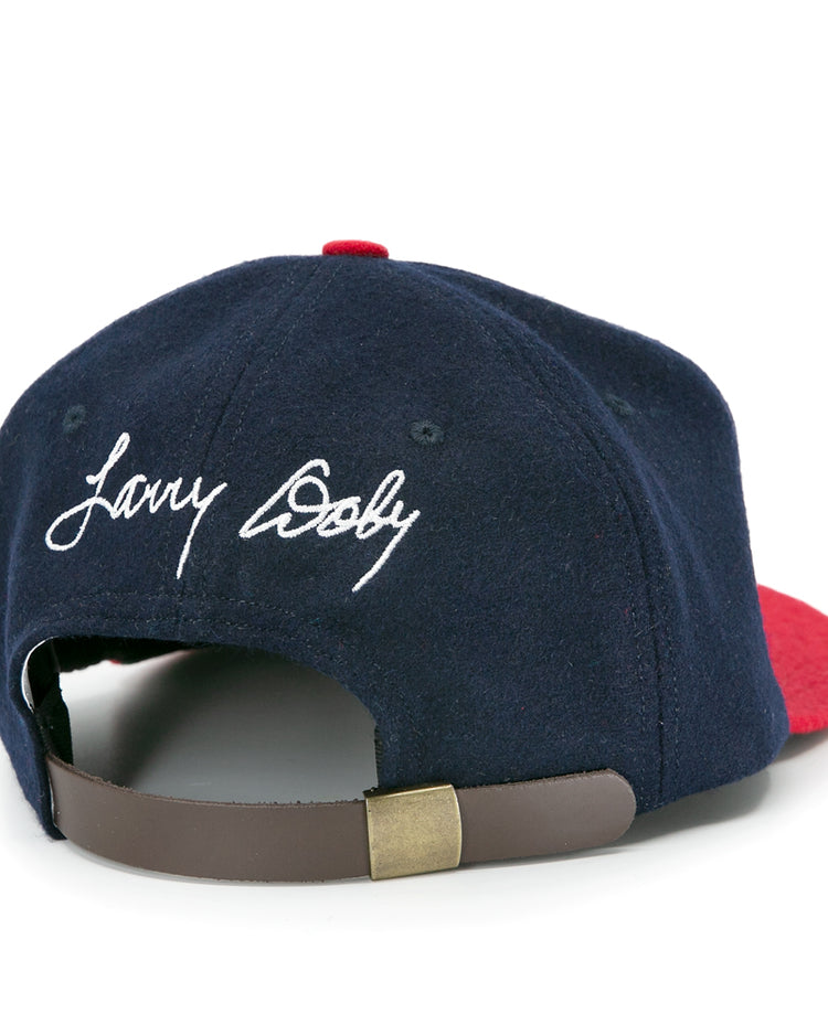 The Ebbets Field Flannels Larry Doby Signature Series Ballcap, in navy blue and red, features his name in white script above an adjustable brown leather strap with a brass clasp—a timeless limited edition cap.