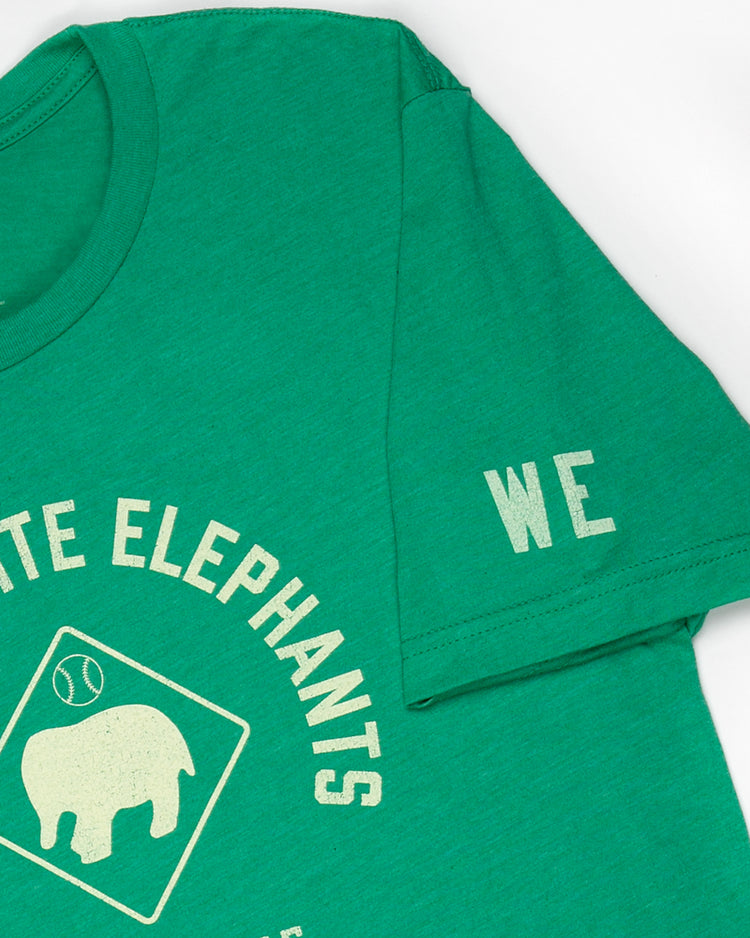 The EFF Denver White Elephants T-Shirt features green fabric with white text, a white elephant graphic, and WE on the sleeve—honoring White Elephants and Black entrepreneurship. Laid flat on a white background.