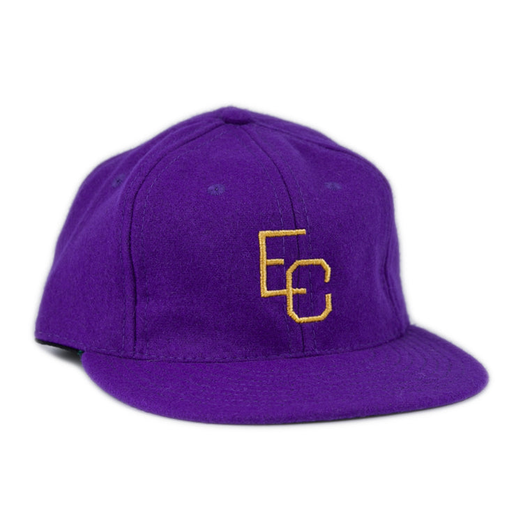 The Ebbets Field Flannels East Carolina University 1961 Vintage Ballcap is a purple wool cap with interlocking yellow EC letters on the front, shown at a slight angle against a white background.