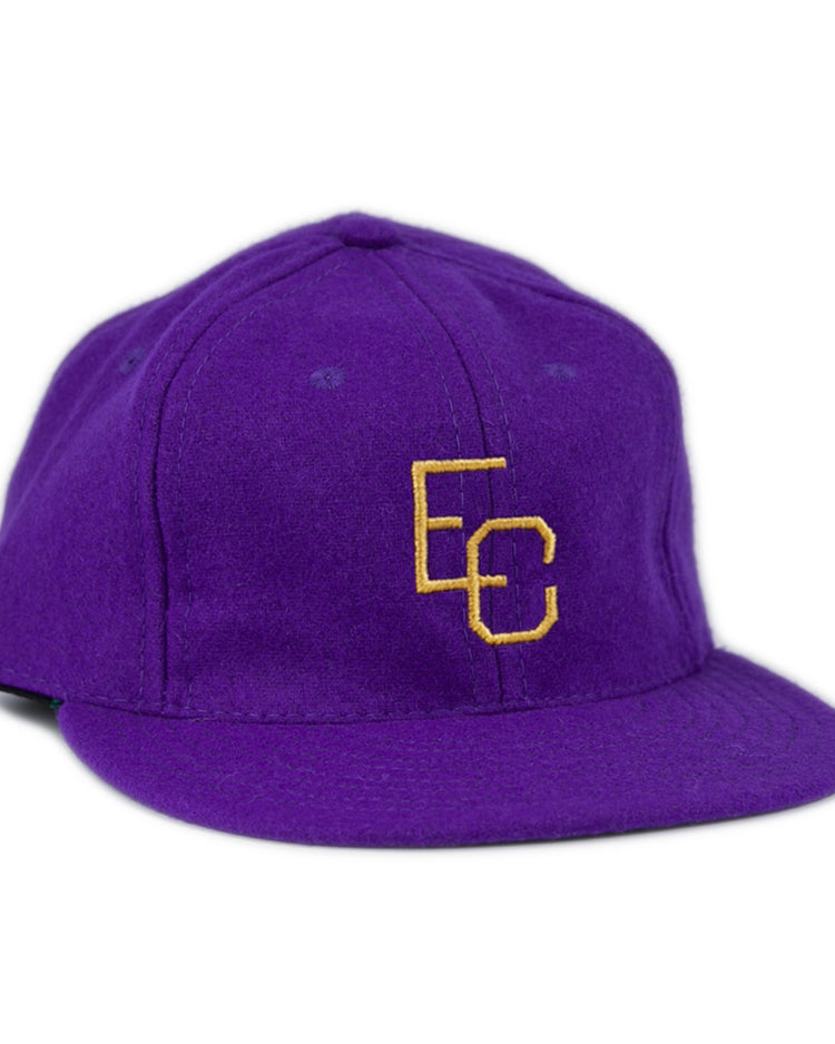The Ebbets Field Flannels East Carolina University 1961 Vintage Ballcap is a purple wool cap with interlocking yellow EC letters on the front, shown at a slight angle against a white background.