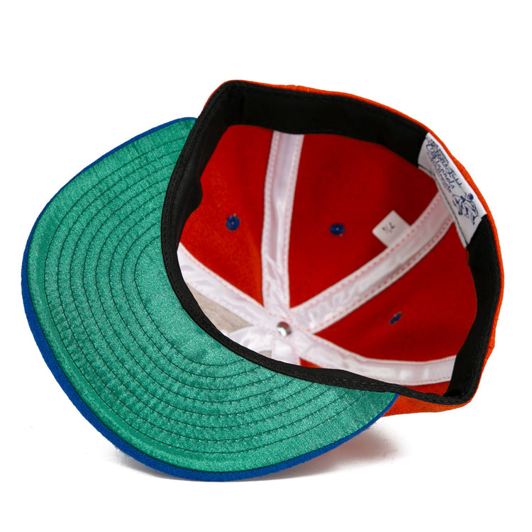 A close-up of the Ebbets Field Flannels University of Cincinnati 1960 Vintage Ballcap, featuring a green undervisor, red crown, blue accents, white seams, and sizing tag—an authentic reproduction of the classic ballcap.