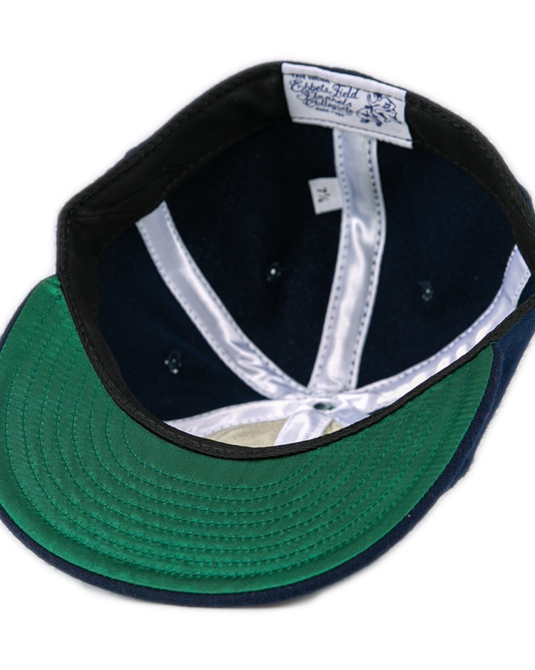 An overhead view of the Fresno State University 1958 Vintage Ballcap by Ebbets Field Flannels, featuring a green underbrim, navy blue interior, white seams, and a white label with blue text stitched into the wool headband.