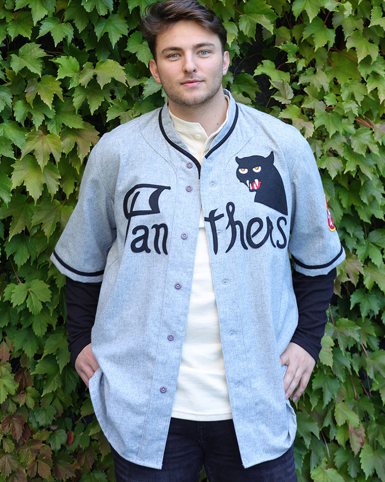 A person stands before a green leafy wall, wearing an EFF Fungo Shirt with black sleeves and logo, hands in pockets, looking at the camera with a neutral expression.