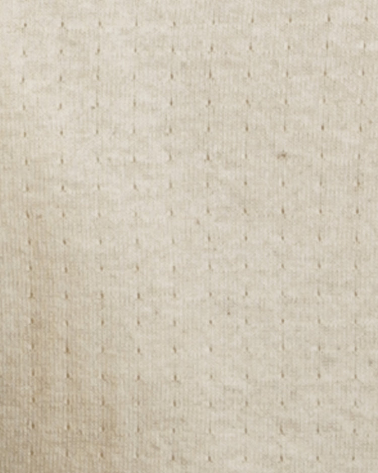 Close-up of the EFF Fungo Shirt, featuring a beige, textured knit fabric with a subtle grid of small raised dots. The soft material recalls vintage wool blends, while black sleeves and logo add a modern touch.