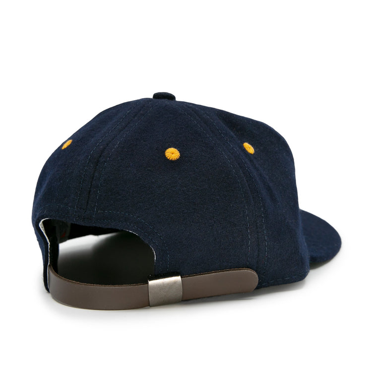 The EFF Great Lakes Naval Station 1944 Vintage Ballcap is a navy wool cap with yellow stitched eyelets, a brown adjustable strap, and a metal clasp, capturing the authentic look of classic 1940s baseball caps.