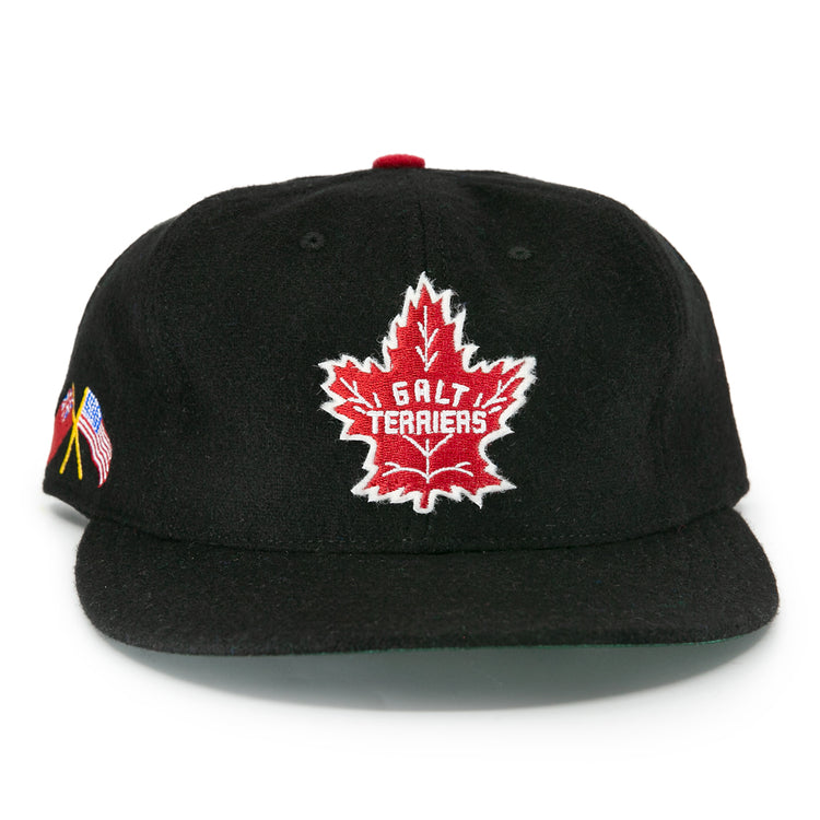 The EFF Galt Terriers 1961 Vintage Ballcap is a black wool hat with a red maple leaf and Galt Terriers on the front, plus small American and German flags on the side, honoring their Ontario Senior Hockey League legacy.