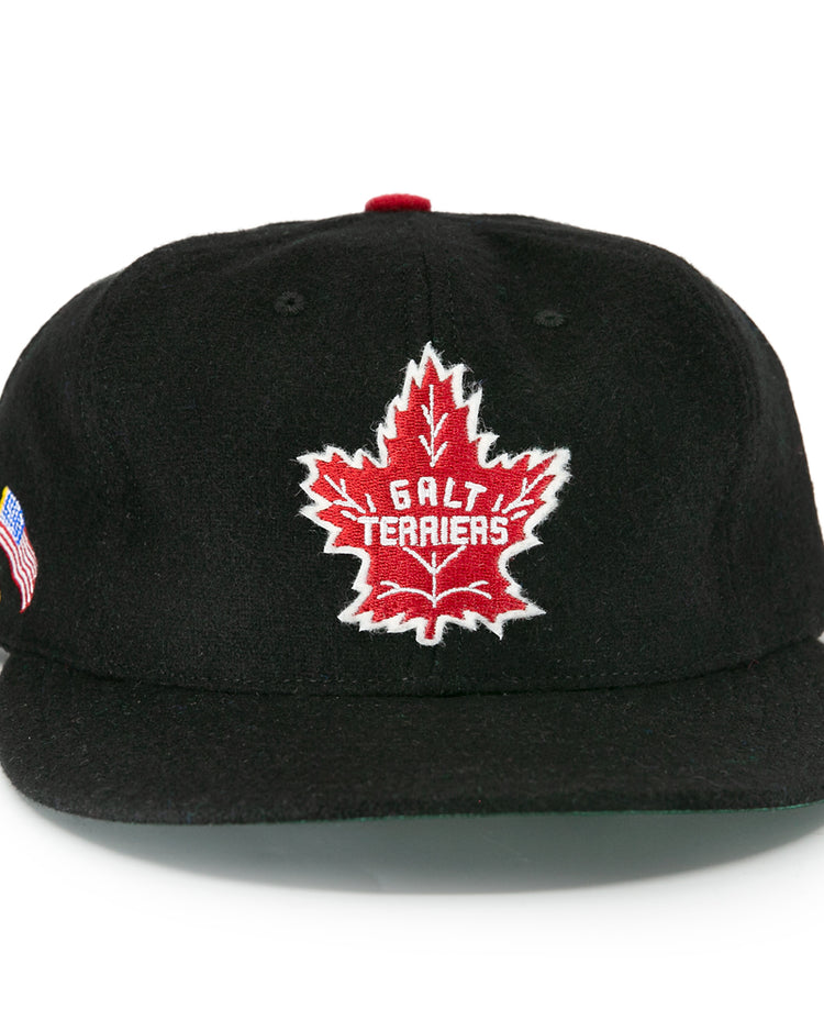The EFF Galt Terriers 1961 Vintage Ballcap is a black wool hat with a red maple leaf and Galt Terriers on the front, plus small American and German flags on the side, honoring their Ontario Senior Hockey League legacy.