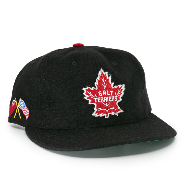 The EFF Galt Terriers 1961 Vintage Ballcap is a black wool cap featuring a red and white maple leaf Galt Terriers logo on the front and crossed Canadian and American flags on the side, honoring Ontario Senior Hockey League history.
