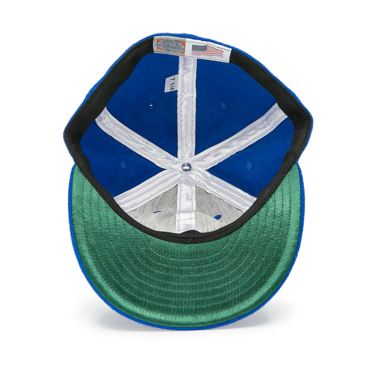 A top-down view shows the inside of the EFF Houston Buffs 1960 Vintage Ballcap, highlighting its blue wool fabric, green underbill, white stitching, plus size and American flag labels.