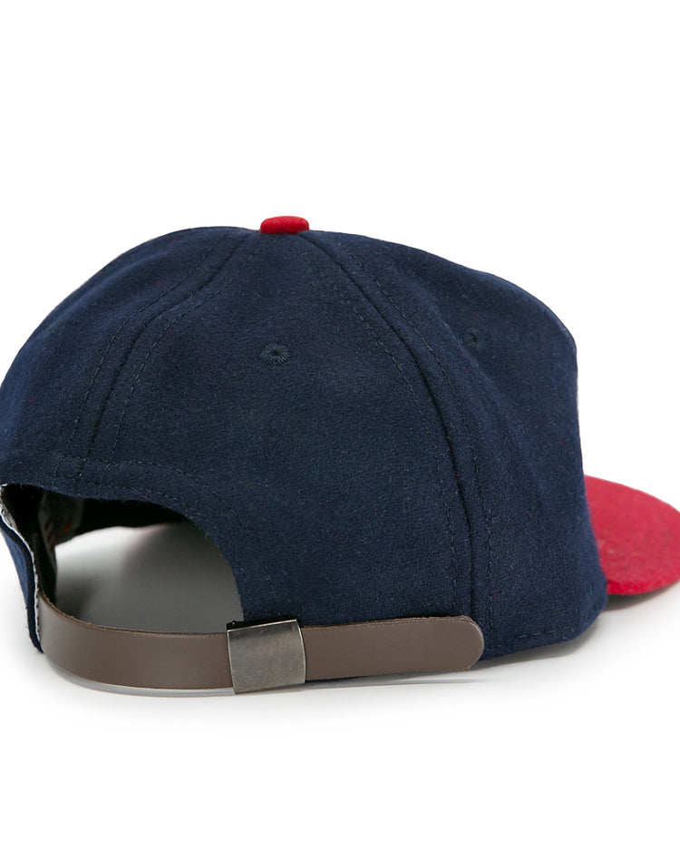 The Jacksonville Braves 1953 Vintage Ballcap by Ebbets Field Flannels is a navy blue cap with a red brim and top button, shown from the back with an adjustable brown leather strap and metal clasp.