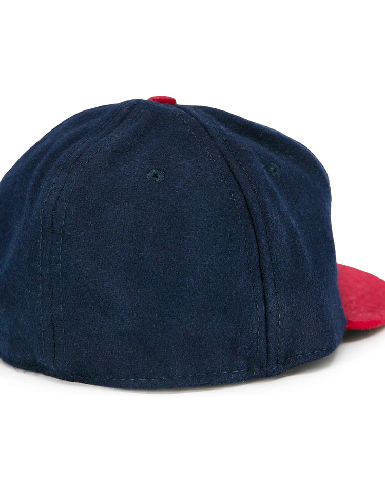 The Ebbets Field Flannels Jacksonville Braves 1953 Vintage Ballcap features soft navy fabric with a red brim, visible panel stitching, and is shown from the back at an angle—capturing the classic look of the original.