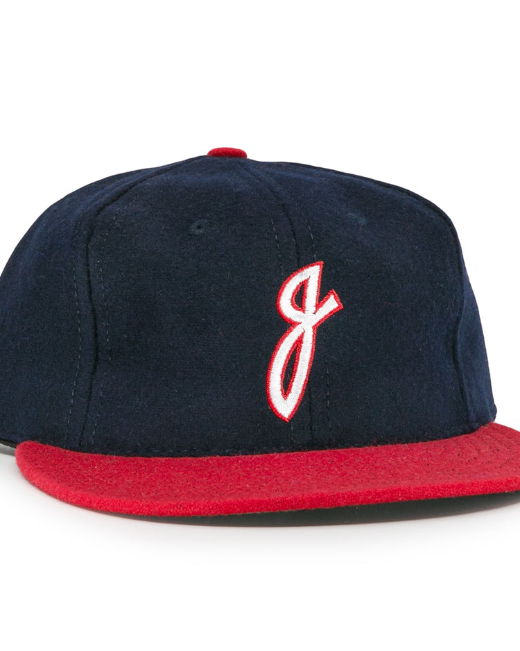 The Ebbets Field Flannels Jacksonville Braves 1953 Vintage Ballcap features navy wool, a red brim, and a white embroidered J outlined in red, inspired by the original 1953 team design.