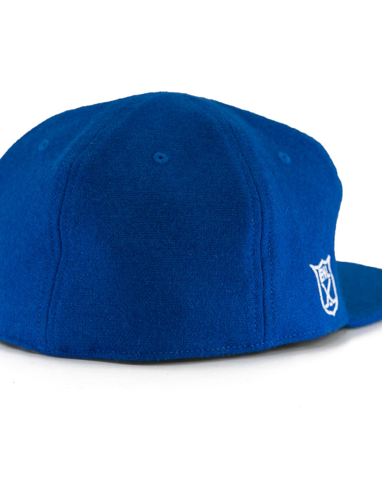 The EFF Johnstown Jets 1970 Vintage Ballcap in royal blue wool is shown from the back and side, featuring a small white embroidered shield logo on the lower right and an adjustable leather strap for a timeless look.