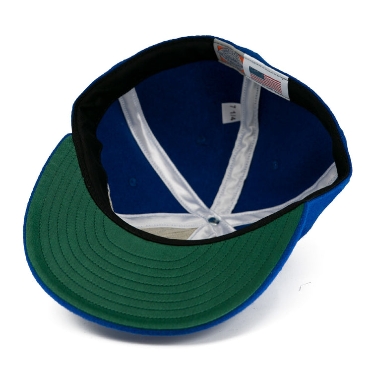 The image shows the interior of an EFF Johnstown Jets 1970 Vintage Ballcap, featuring a blue wool exterior, green brim underside, white inner seams, a “7 1/4” size tag, and an American flag label.
