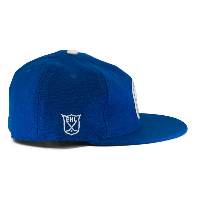 The EFF Johnstown Jets 1970 Vintage Ballcap is royal blue with a white embroidered EHL shield logo on the side, a white top button, and an adjustable leather strap, shown from a side angle.