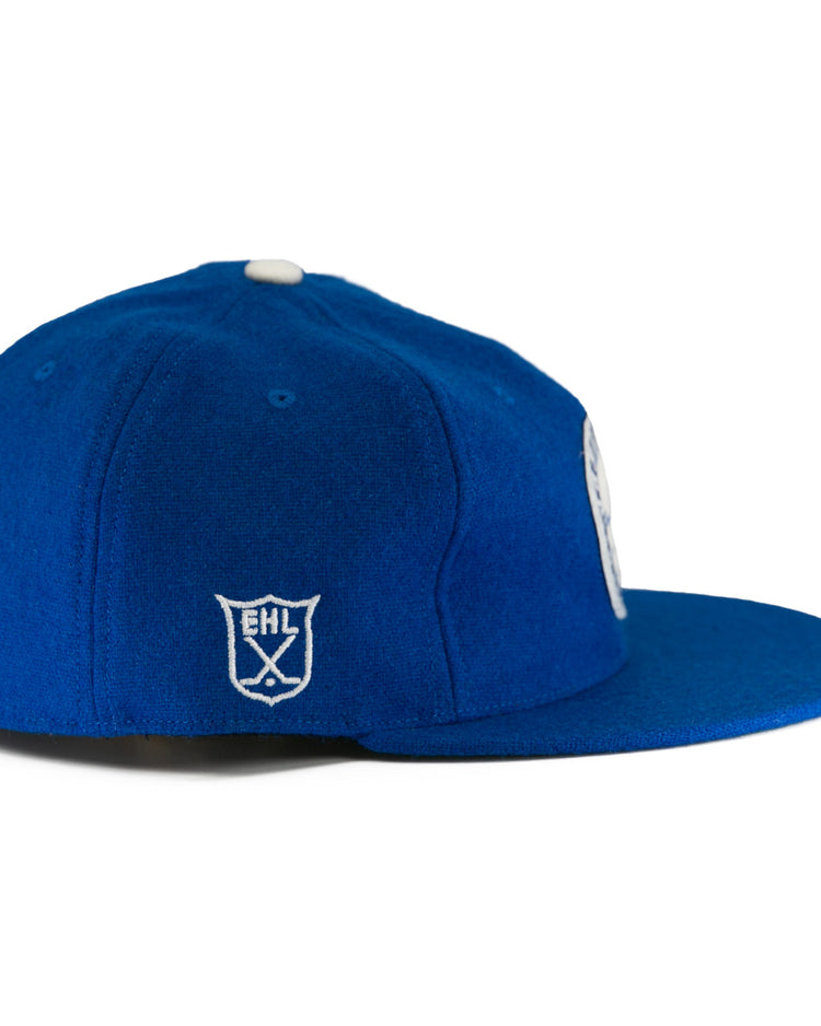 The EFF Johnstown Jets 1970 Vintage Ballcap is royal blue with a white embroidered EHL shield logo on the side, a white top button, and an adjustable leather strap, shown from a side angle.