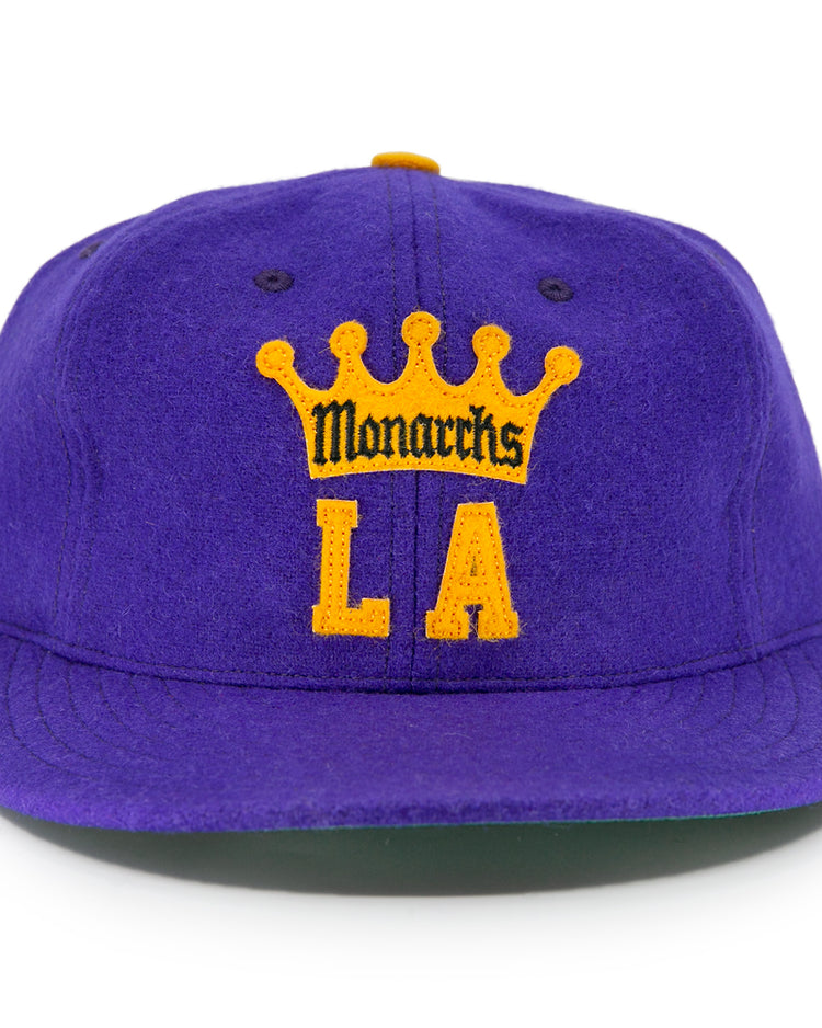 The EFF Los Angeles Monarchs 1947 Vintage Ballcap is a purple wool hat with a yellow crown, featuring Monarchs above bold yellow LA letters on the front, honoring the teams Western Hockey League history.