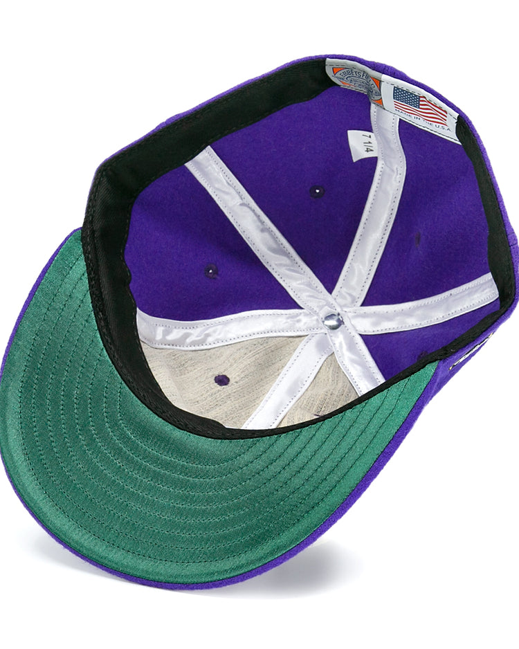The image shows the inside of an EFF Los Angeles Monarchs 1947 Vintage Ballcap, a purple wool hat with a green brim, white lining strips, a sewn-in tag, and a small American flag tag.
