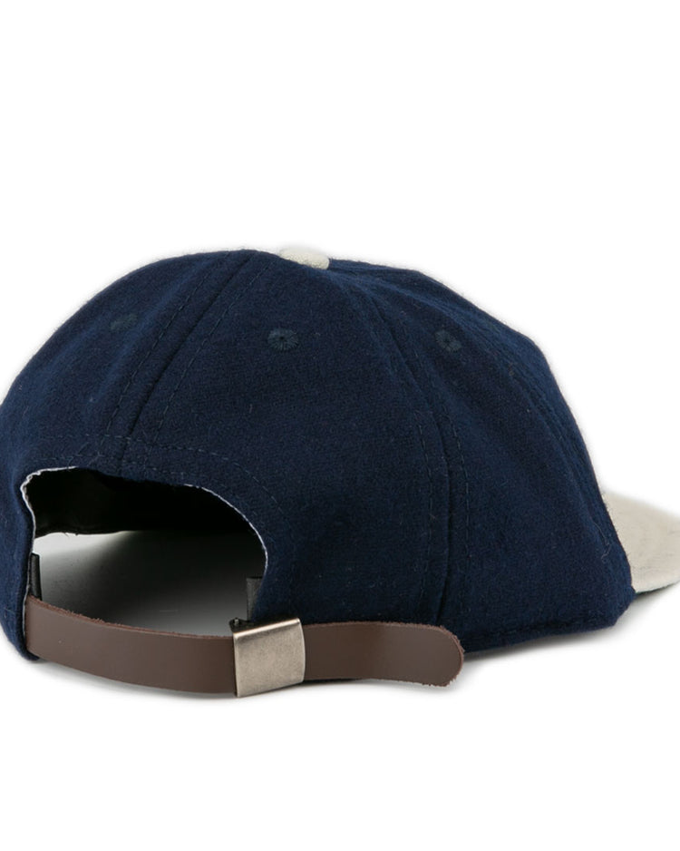 The EFF Larrupin’ Lou’s 1927 Vintage 8-Panel Ballcap features navy blue fabric, a curved brim, and a tan adjustable leather strap at the back, shown against a white background.