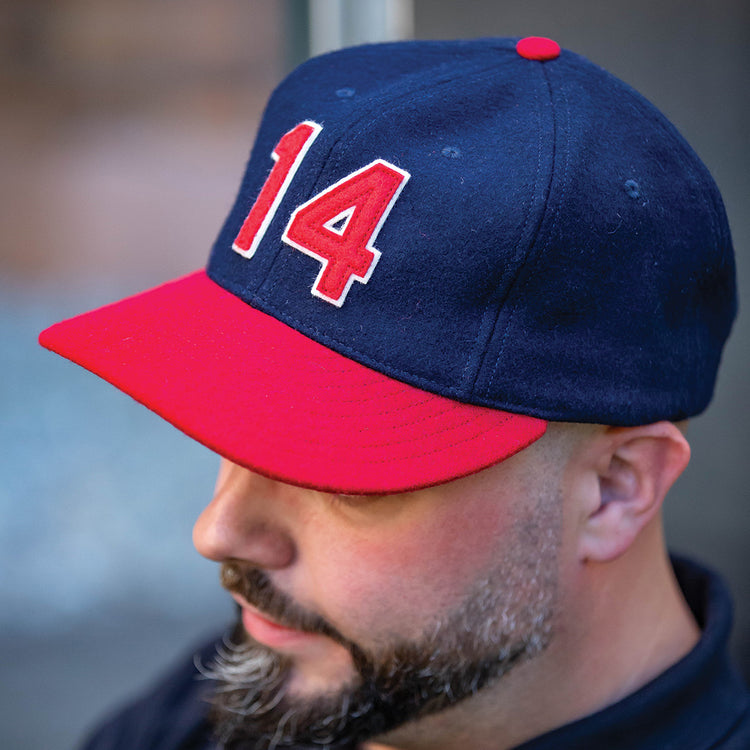 A man with a trimmed beard wears an Ebbets Field Flannels Larry Doby Signature Series Ballcap in navy blue, featuring a red brim and the number 14 in red and white on the front.