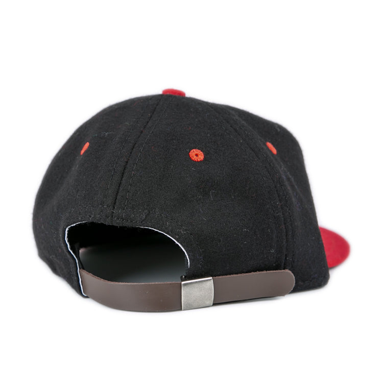 The EFF University of Maryland 1939 Vintage Ballcap is a black hat with red eyelets, a brown adjustable strap with metal clasp, and a partially visible red brim, viewed from the back.