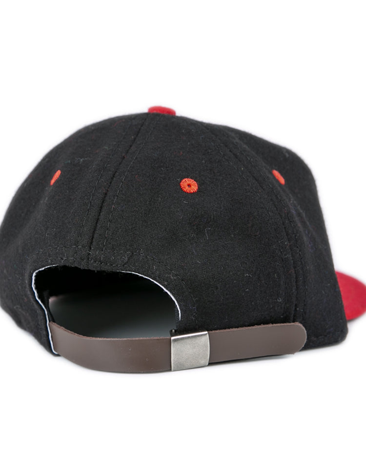 The EFF University of Maryland 1939 Vintage Ballcap is a black hat with red eyelets, a brown adjustable strap with metal clasp, and a partially visible red brim, viewed from the back.